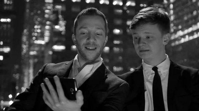 black and white scene of two young man looking at smart phone talking together