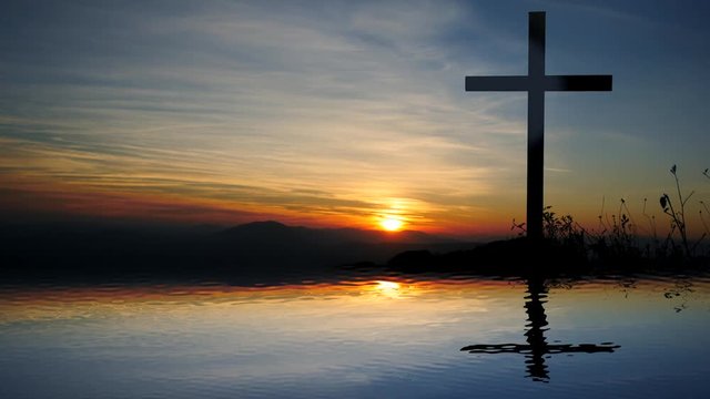 water reflection of religious cross in landscape at sunset