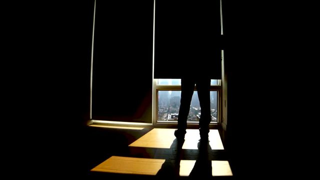 silhouette of man in modern office in the city standing on large window front