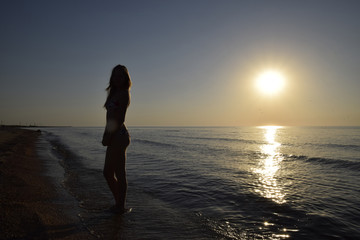 Silhouette of a girl against the sunset by the sea