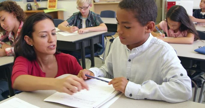 Teacher helps schoolboy in class, close up, 