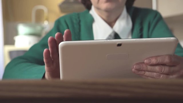 DOLLY: Close up of a white tablet PC in a aged woman hands