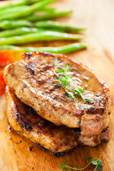 pork chops with thyme and vegetable on wooden board