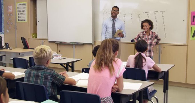 Kids applauding schoolgirl at front of class, 