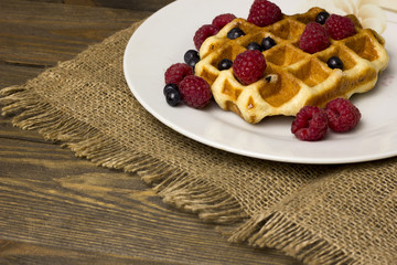 Belgian waffles on a wooden table with berries