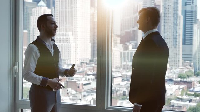 two caucasian business partners meeting in modern office talking together