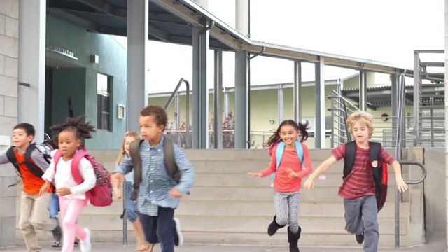 Young school kids jumping down steps as they leave school