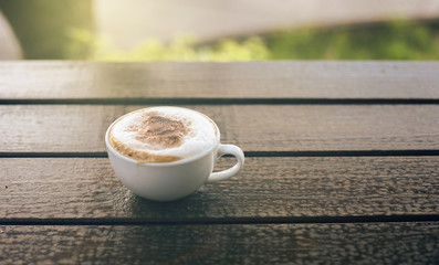 Cup of coffee on wooden table with blurred background,warm tone picture,filtered image,selective focus,light effect added