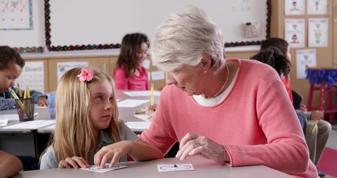 Surprised teacher helps young schoolgirl tell time in class