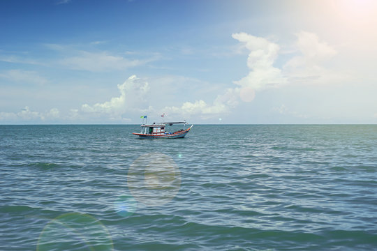 traditional fishing boat laying alone on the sea,selective focus,filtered image,light and flare effect added