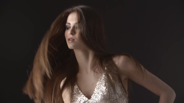 Young woman in evening dress tosses head and flicks her hair