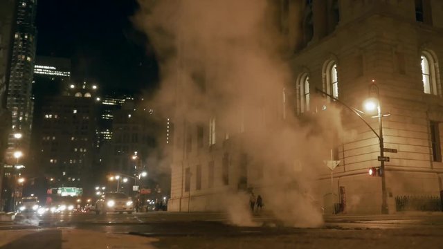 cars driving over steam smoke city street at night