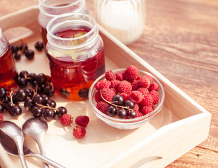 Tea with ripe raspberry and blackcurrant. Food composition on a wooden background. Selective focus.