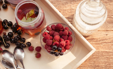 Tea with ripe raspberry and blackcurrant. Food composition on a wooden background. Selective focus.