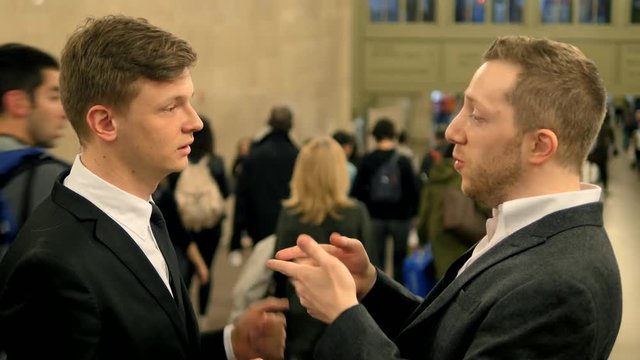 business partner talking together in crowded train station. young caucasian man