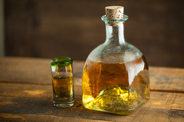 Gold tequila in glass on wood table. Selective Focus. Blurred background.