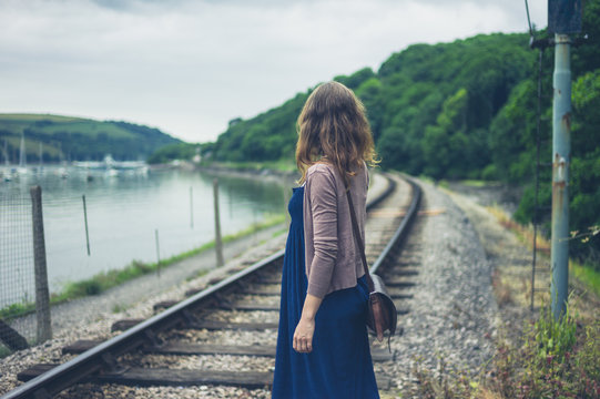 Woman walking by railroad tracks and river