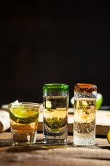 Shot glass of tequila on wood table. Selective focus. Blurred background.