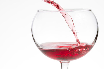 Red wine pouring into a wine glass with copy space
