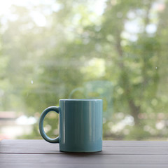 reinforcement force warm mood/ blue cup on a wooden table, against the window with a sunny summer day 