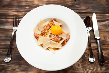 Italian Pasta Carbonara on white plate with parmesan and yolk on
