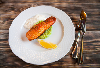 Grilled Salmon with slice of lemon and white sause on wooden bac