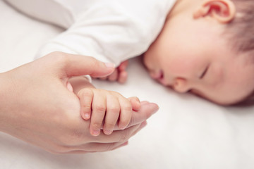 Fototapeta na wymiar Hand the sleeping baby in the hand of mother close-up (Soft focu