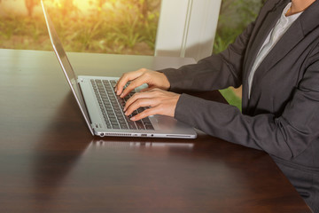 Business women typing and working with laptop in the workplace and sunlight.