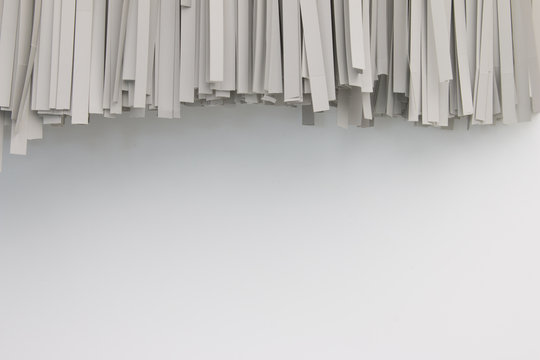 Paper shredded on white background. Paper shredder hang on white wall. Shredded documents on wall.