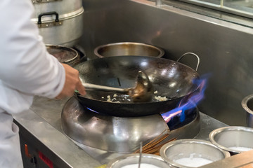 Male chef cooking in a frying pan on a kitchen
