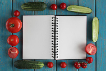 Note book and composition of vegetables on blue wooden desk.