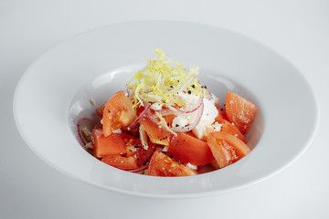 vegetable salad with tomatoes and mozzarella in a white plate