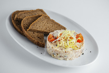 russian salad with tomato and black bread on a white plate