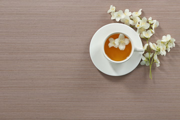 Cup of tea with jasmine flowers on wooden background