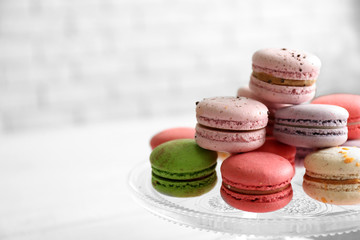 Colorful tasty macaroons in glass stand on light background