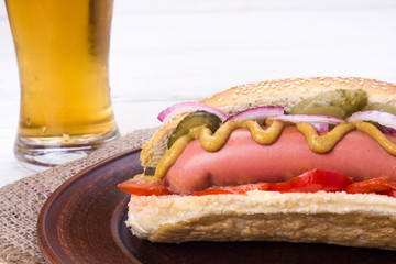 hot dog shot at close range on a white background with a glass of beer