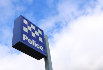 blue and white police station sign in bright blue sky