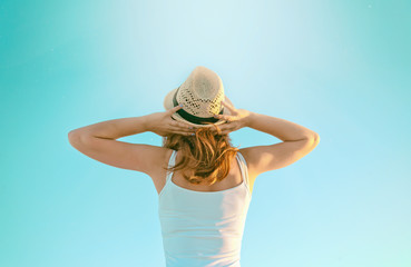 Young girl in a hat against the blue sky. Vacation and travel co