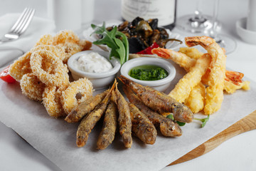 squid rings in batter, fish, mussels and shrimp on a wooden tray