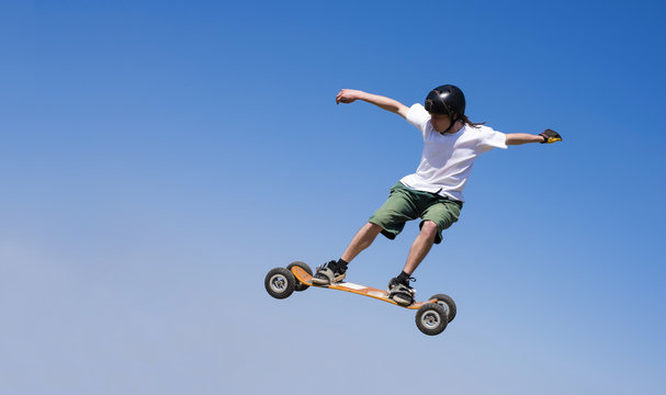 Skateboarder doing a jumping trick at skateboard park with mountainboard