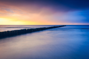 Fototapeta premium sunset on the beach with a wooden breakwater, long exposure