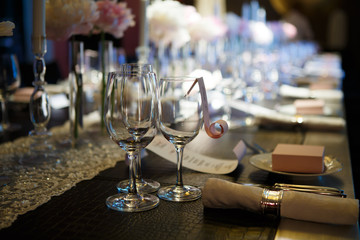 Wine glasses on table covered in, glasses and plates, forks and knives, napkins and buttons for a luxurious celebration in anticipation of guests, luxury festive table. 