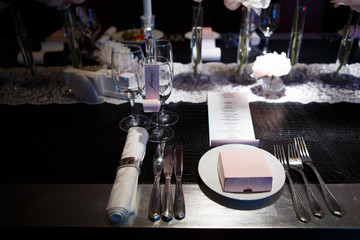 Cutlery luxury table covered in natural crocodile skin. Glasses and plates, forks and knives, napkins and buttons for a luxurious celebration in anticipation of guests. Luxury festive table. 