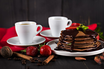 .chocolate pancakes with chocolate sauce and strawberries. coffee. breakfast