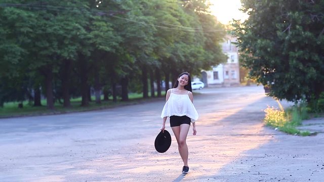 Cute female Young beautiful Asian girl in the green park sun background portrait, look to camera and shows emotions happy and rejoices walking doing to camera
