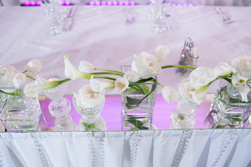 Beautiful restaurant interior table decoration for wedding. Flower . White calla lilies and tulips in vases. Candles