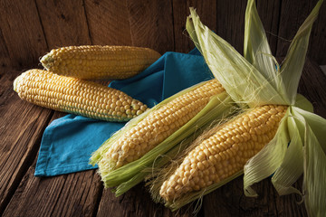 Fresh corn on cobs on wooden table