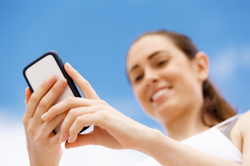 Female runner with her mobile smart phone standing outdoors