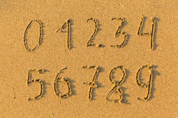Numbers from 0 to 9 hand-drawn in the beach sand.