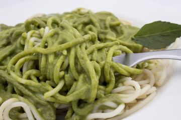 Italian pasta spaghetti with pesto sauce and basil leaf close-up.